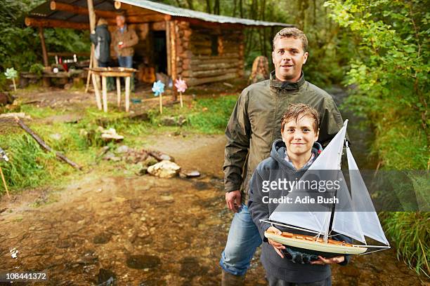 father and son holding sailing boat - spielzeugschiff stock-fotos und bilder