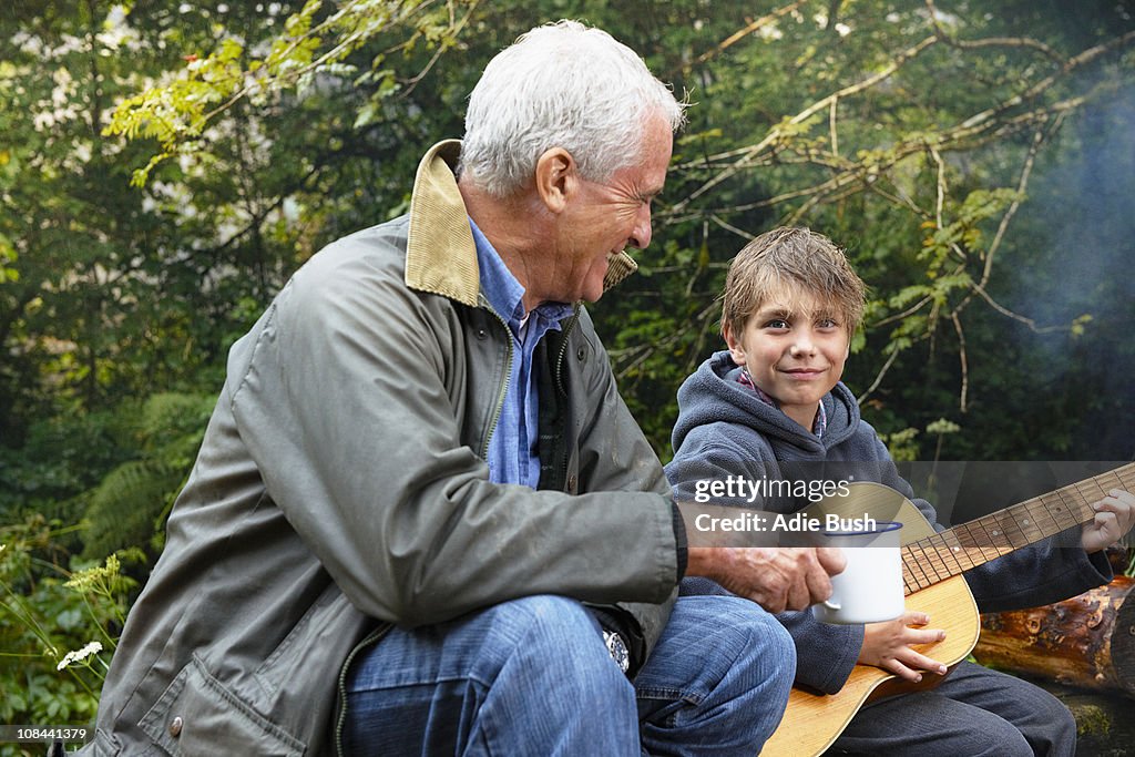 Grandfather and grandson by campfire