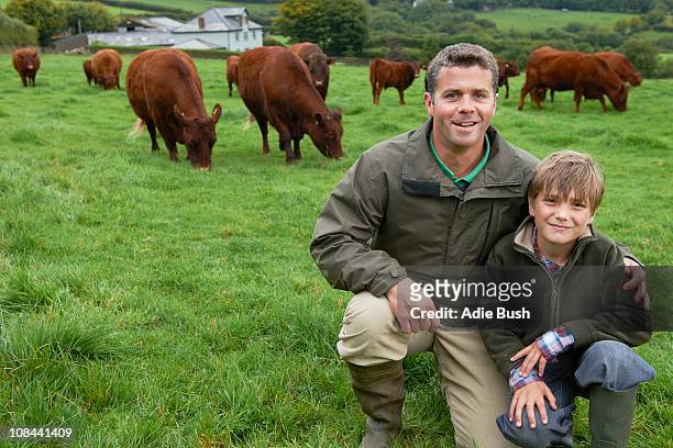 father and son on farm with cows - cow cuddling stock pictures, royalty-free photos & images