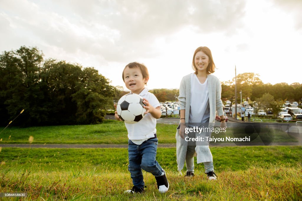 Son who plays with soccer ball, mother watching over.