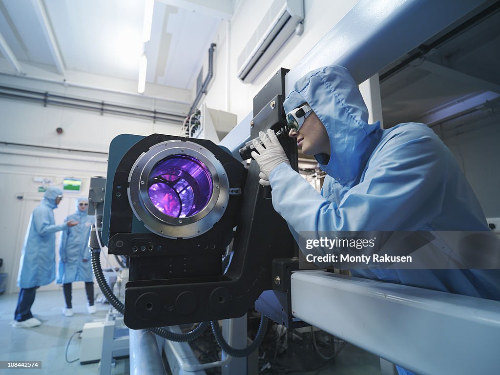 Scientists in protective clothing and goggles in laboratory next to laser equipment