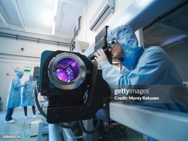 scientists in protective clothing and goggles in laboratory next to laser equipment - láser fotografías e imágenes de stock