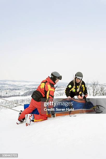 two rescuers helping skier - rescue worker fotografías e imágenes de stock