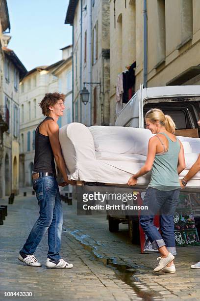 couple moving sofa in street - moving sofa stock pictures, royalty-free photos & images