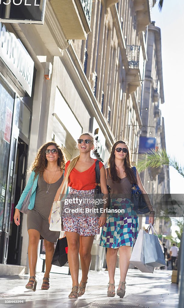 Young women walk in street with bags