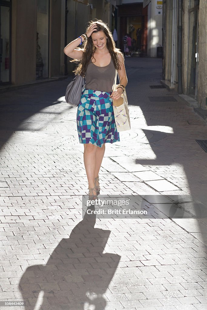 Young woman walks in street with bags