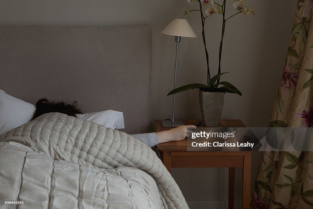 Young woman switching off phone alarm