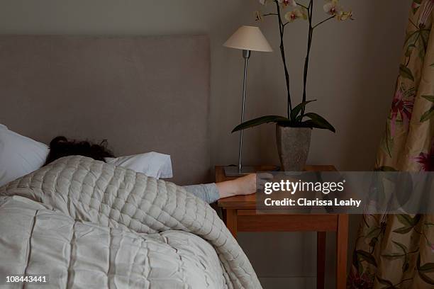 young woman switching off phone alarm - night table stock pictures, royalty-free photos & images