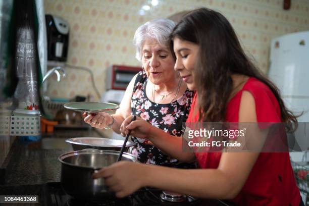 oma haar kleindochter onderwijzen hoe te koken - cooking together stockfoto's en -beelden