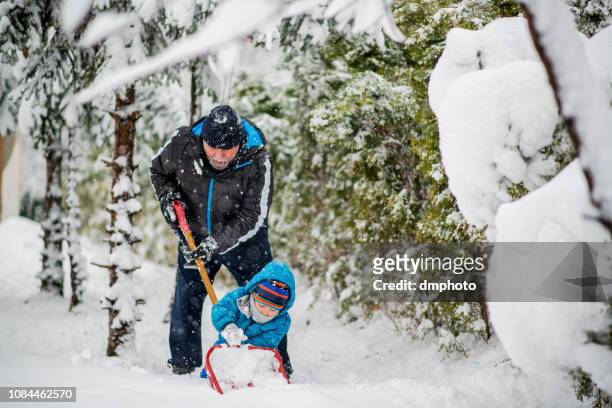 großvater und enkel reinigung schnee an einem wintertag - grandfather child snow winter stock-fotos und bilder