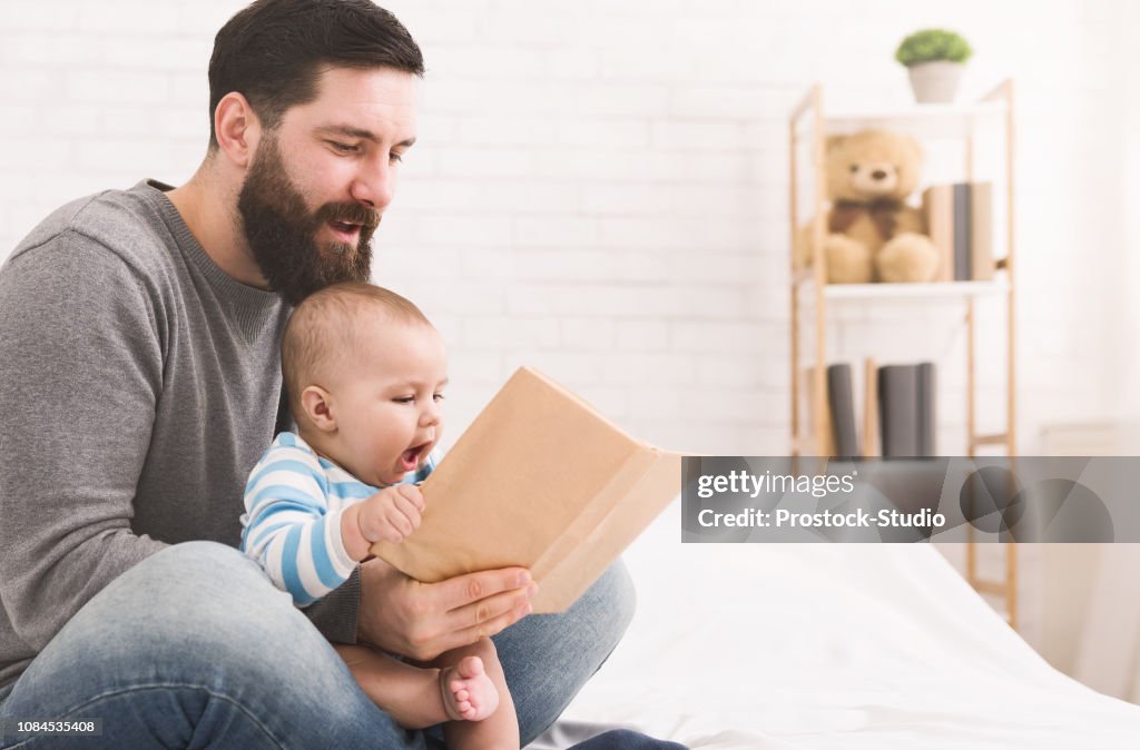 Father reading book to little baby son