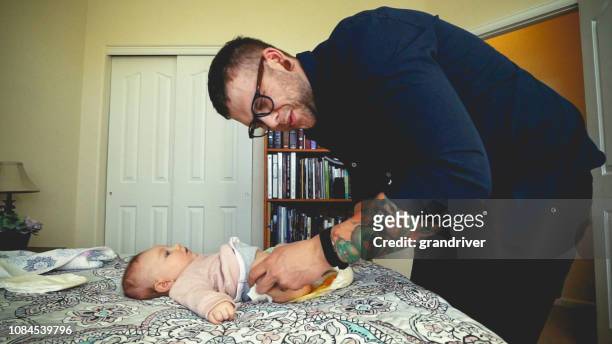 twenty something hipster dad changing a very poopy diaper of his infant daughter - changing diaper stock pictures, royalty-free photos & images