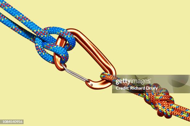 two coloured ropes tied to carabiner - bergbeklimartikelen stockfoto's en -beelden