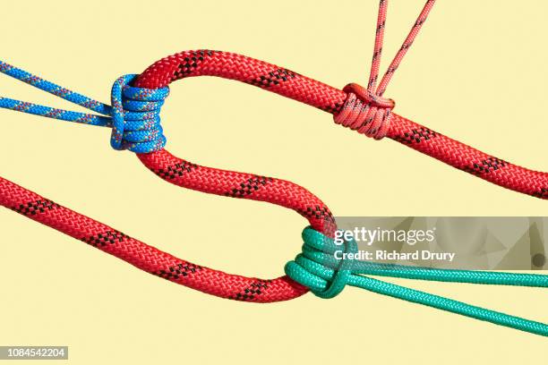 three coloured ropes pulling on a larger rope to shape its path - knoten stock-fotos und bilder