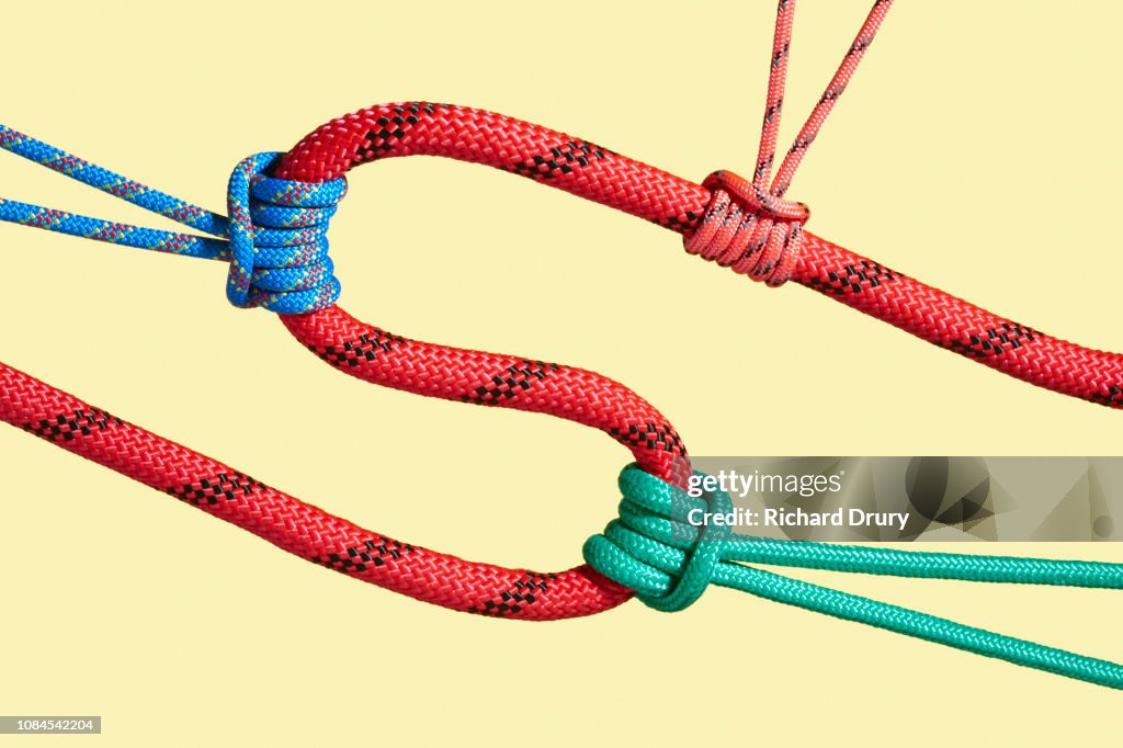 Three coloured ropes pulling on a larger rope to shape its path