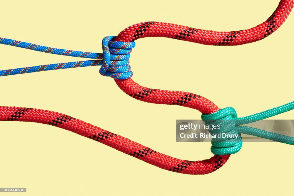 Two ropes pulling on a larger rope to shape its path