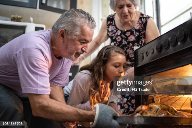 abuelos y nieta comprobando el tradicional pavo para la cena de navidad - brazil open fotografías e imágenes de stock