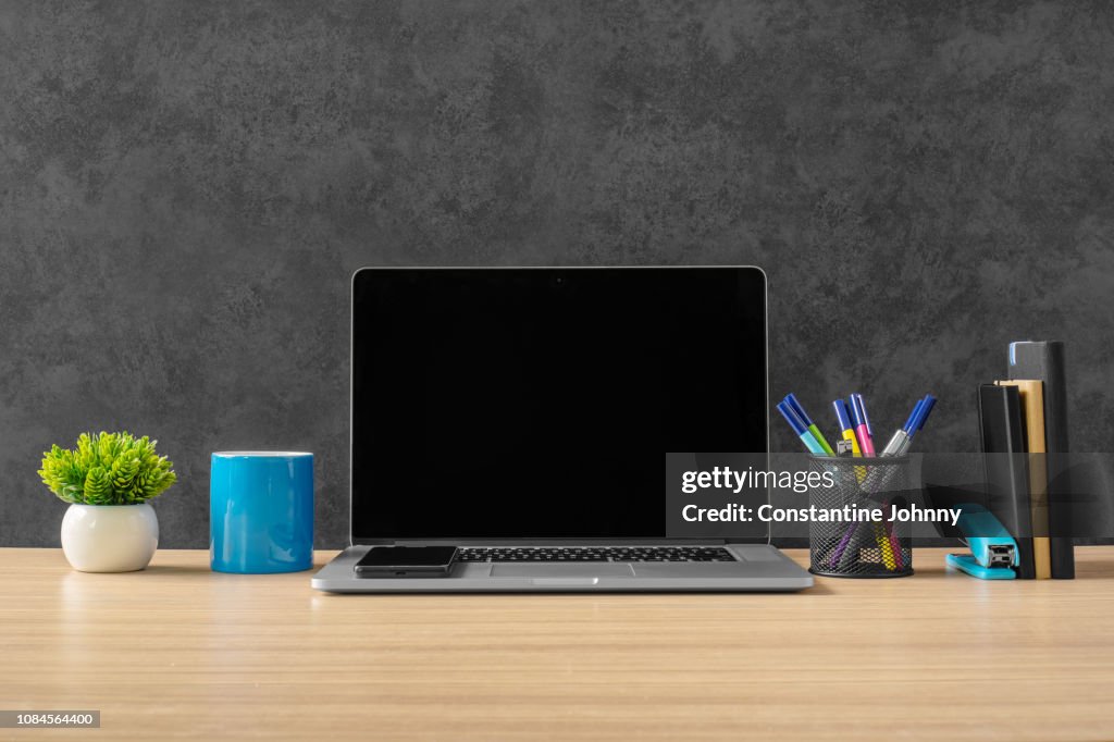 Laptop, Office Supply Items and Blue Coffee Mug on Office Desk.