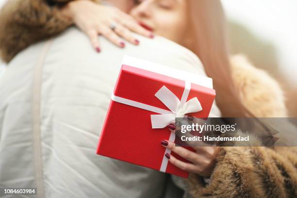 sonriente mujer celebración de día de san valentín regalos y abrazos man - día de san valentín festivo fotografías e imágenes de stock