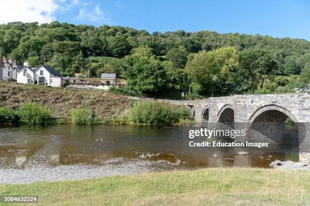 The Grouse Inn and an old stone arched bridge over The River Dee flowing through the Vale of Llangollen, Carrog, Denbighshire, North United Kingdom,...