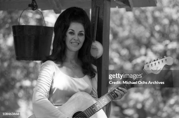 Singer and guitarist Wanda Jackson poses for a portrait session sitting on a well holding a Fender Kingman acoustic guitar in circa 1975.