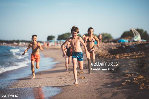 kinderen uitgevoerd en schieten met water pistolen op het strand - bulgarije stockfoto's en -beelden