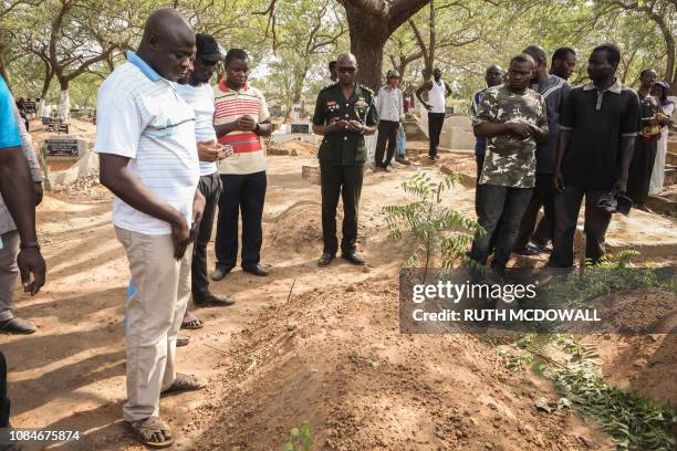 Mourners stand beside the grave of slain Ghanaian investigative journalist Ahmed Husein Suale during his funeral in Accra, on January 18, 2019. - The...