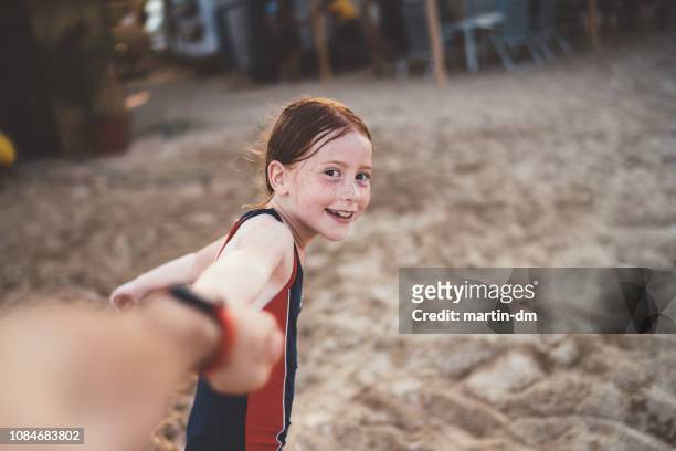 rothaarige mädchen am strand will mit seinem vater spielen - ziehen stock-fotos und bilder