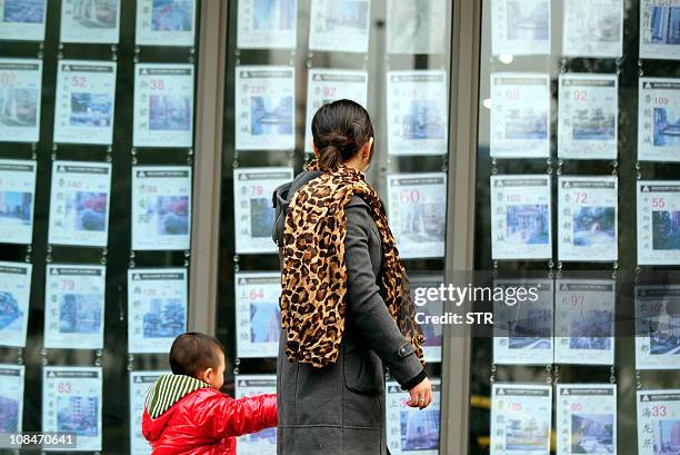 Pedestrians pass a real estate office in southwest China's Chongqing municipality on January 28, 2011. China launched a long-awaited property tax in...