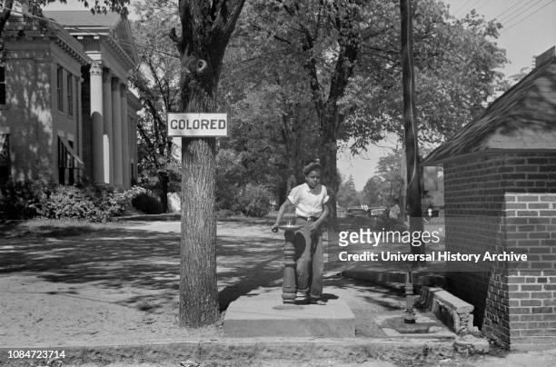 Boy at Drinking Fountain with Sign "Colored" on County Courthouse Lawn, Halifax, North Carolina, USA, John Vachon, Farm Security Administration,...