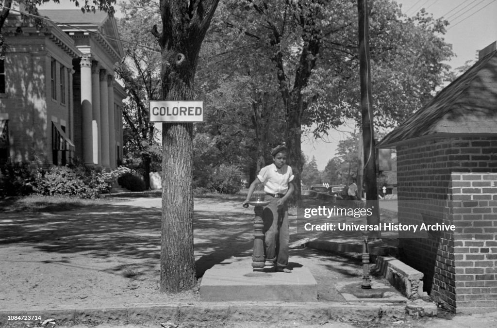 Boy at Drinking Fountain with Sign "Colored" on County Courthouse Lawn, Halifax, North Carolina, USA, John Vachon, Farm Security Administration, April 1938
