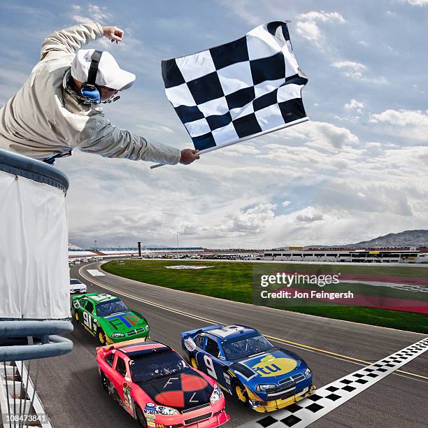 race car crossing the finish line - geblokte vlag stockfoto's en -beelden