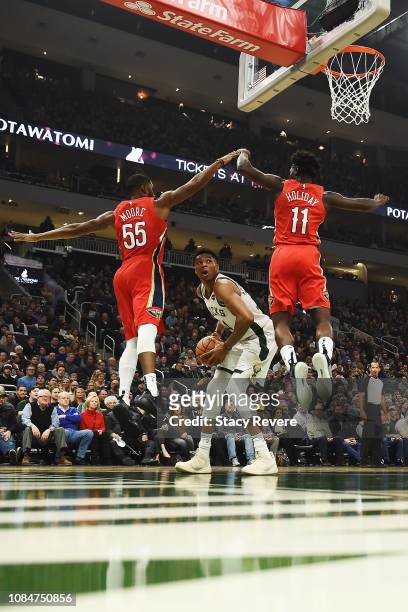 Giannis Antetokounmpo of the Milwaukee Bucks is defended by E'Twaun Moore and Jrue Holiday of the New Orleans Pelicans during the first half of a...