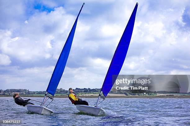 two young women sailing small dinghys. - sailing dinghy stock pictures, royalty-free photos & images