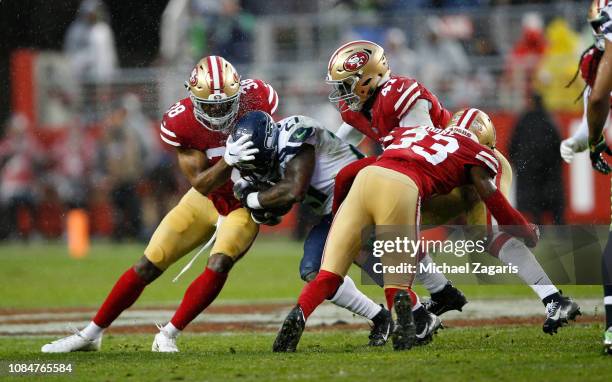 Antone Exum Jr. #38, Elijah Lee and D.J. Reed Jr. #32 of the San Francisco 49ers tackle Mike Davis of the Seattle Seahawks during the game at Levi's...