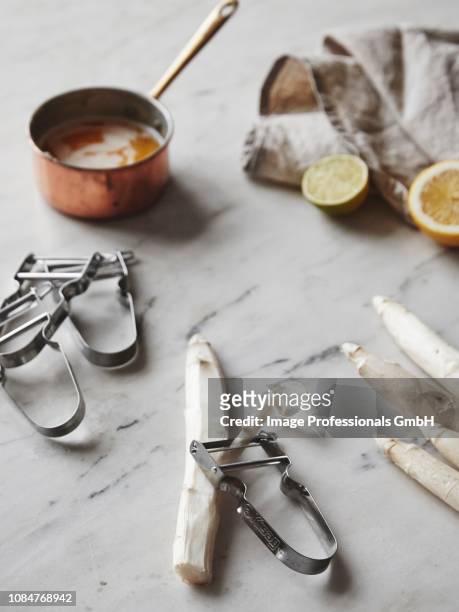 white asparagus with a peeler and a saucepan of brown butter - asparagina foto e immagini stock