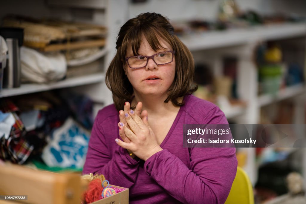 Woman with Down Syndrome weaves at a loom.