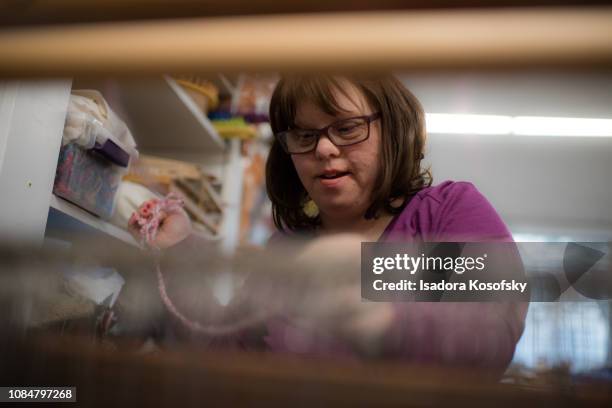 Woman with Down Syndrome weaves at a loom.