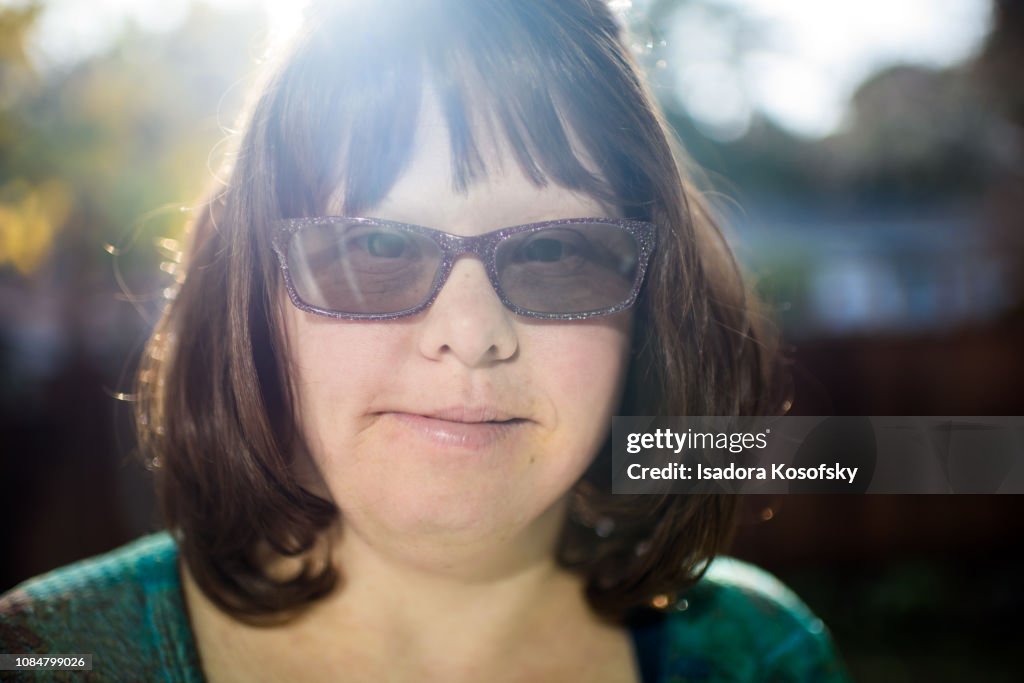 Portrait of woman with Down Syndrome emerging from sunlight