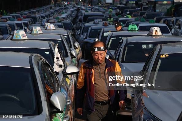 A taxi driver stands amid parked taxis to rally calling for the... News ...