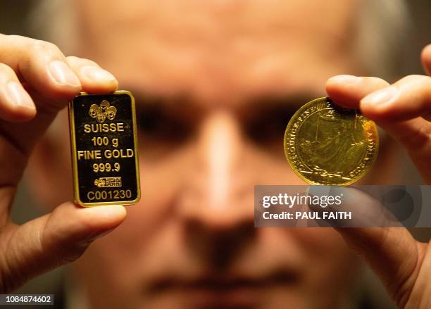 Seamus Fahy, co-founder of Merrion vaults holds up a Swiss 100 gram gold bar and a Brittania 1 ounce gold coint at the Merrion vaults in Dublin on...