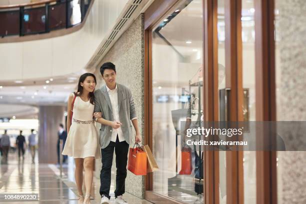 happy couple window shopping in luxury mall - luxury handbag stock pictures, royalty-free photos & images