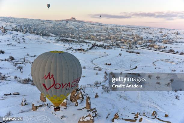 Hot-air balloons glide above fairy chimneys in snow-covered Cappadocia region, located in Central Anatolia's Nevsehir province, Turkey on January 19,...