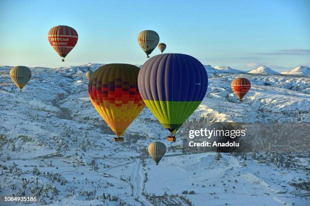 Hot-air balloons glide above fairy chimneys in snow-covered Cappadocia region, located in Central Anatolia's Nevsehir province, Turkey on January 19,...