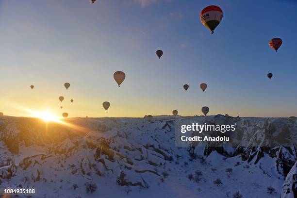 Hot-air balloons glide above fairy chimneys in snow-covered Cappadocia region, located in Central Anatolia's Nevsehir province, Turkey on January 19,...