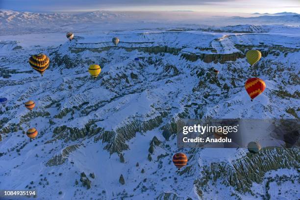 Hot-air balloons glide above fairy chimneys in snow-covered Cappadocia region, located in Central Anatolia's Nevsehir province, Turkey on January 19,...