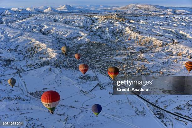 Hot-air balloons glide above fairy chimneys in snow-covered Cappadocia region, located in Central Anatolia's Nevsehir province, Turkey on January 19,...