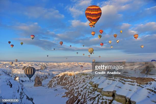 Hot-air balloons glide above fairy chimneys in snow-covered Cappadocia region, located in Central Anatolia's Nevsehir province, Turkey on January 19,...