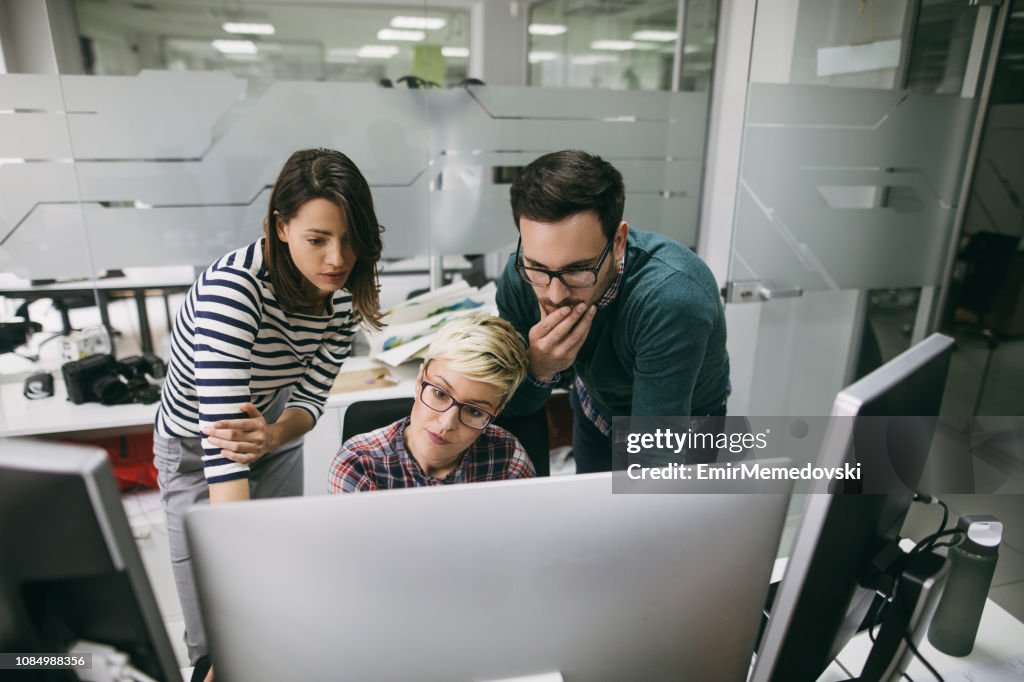 Three web designers working in office on a project together
