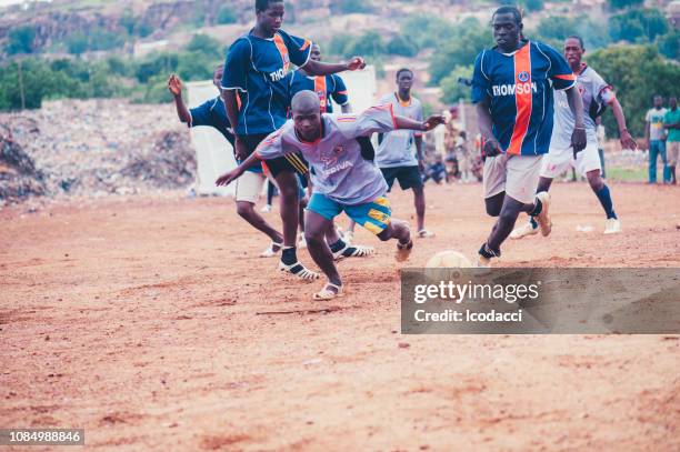 schwarze afrikanische kinder spielen fußball in einer ländlichen gegend - poor kids playing soccer stock-fotos und bilder